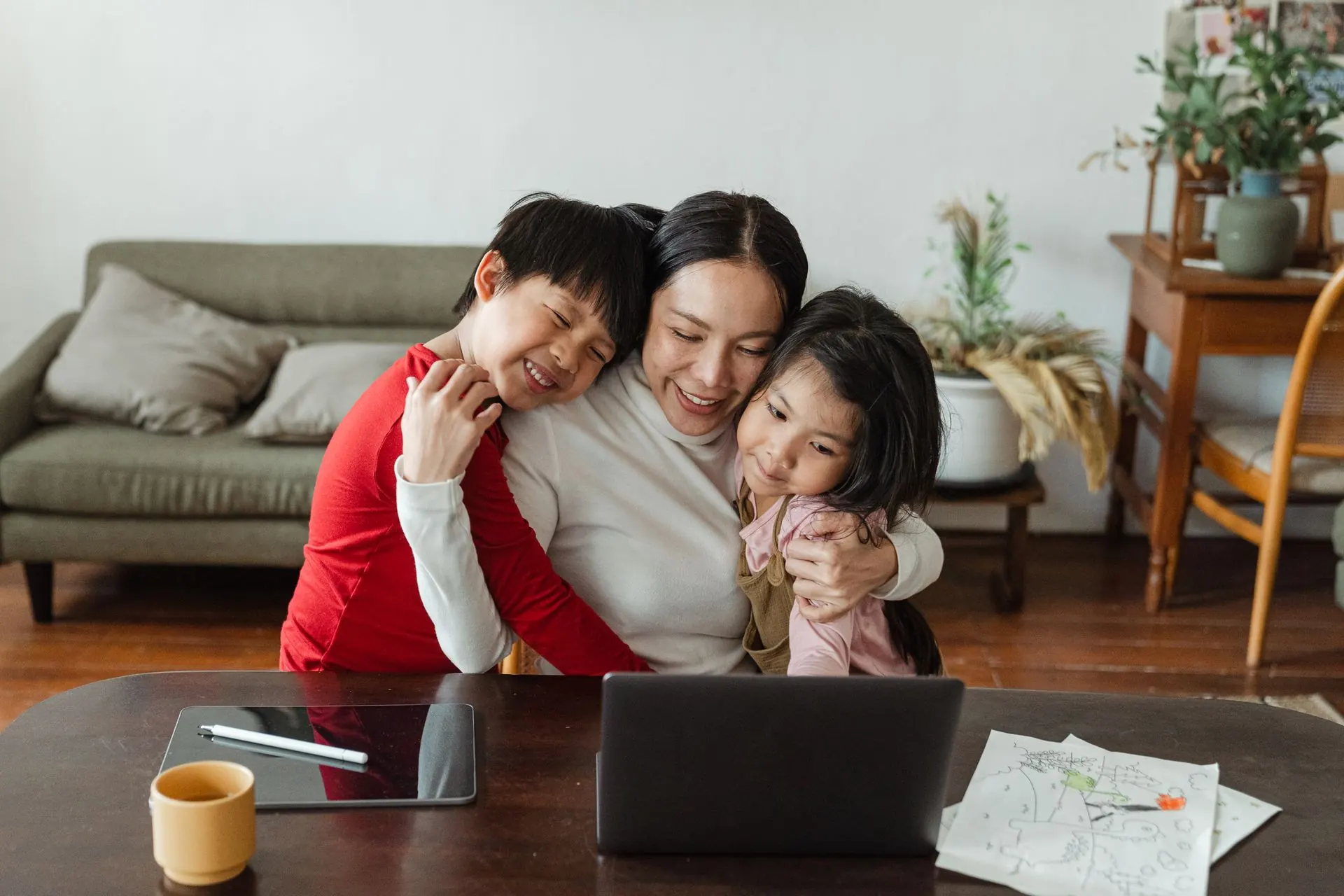 Người mẹ ôm hai con trên ghế sofa trong phòng khách
