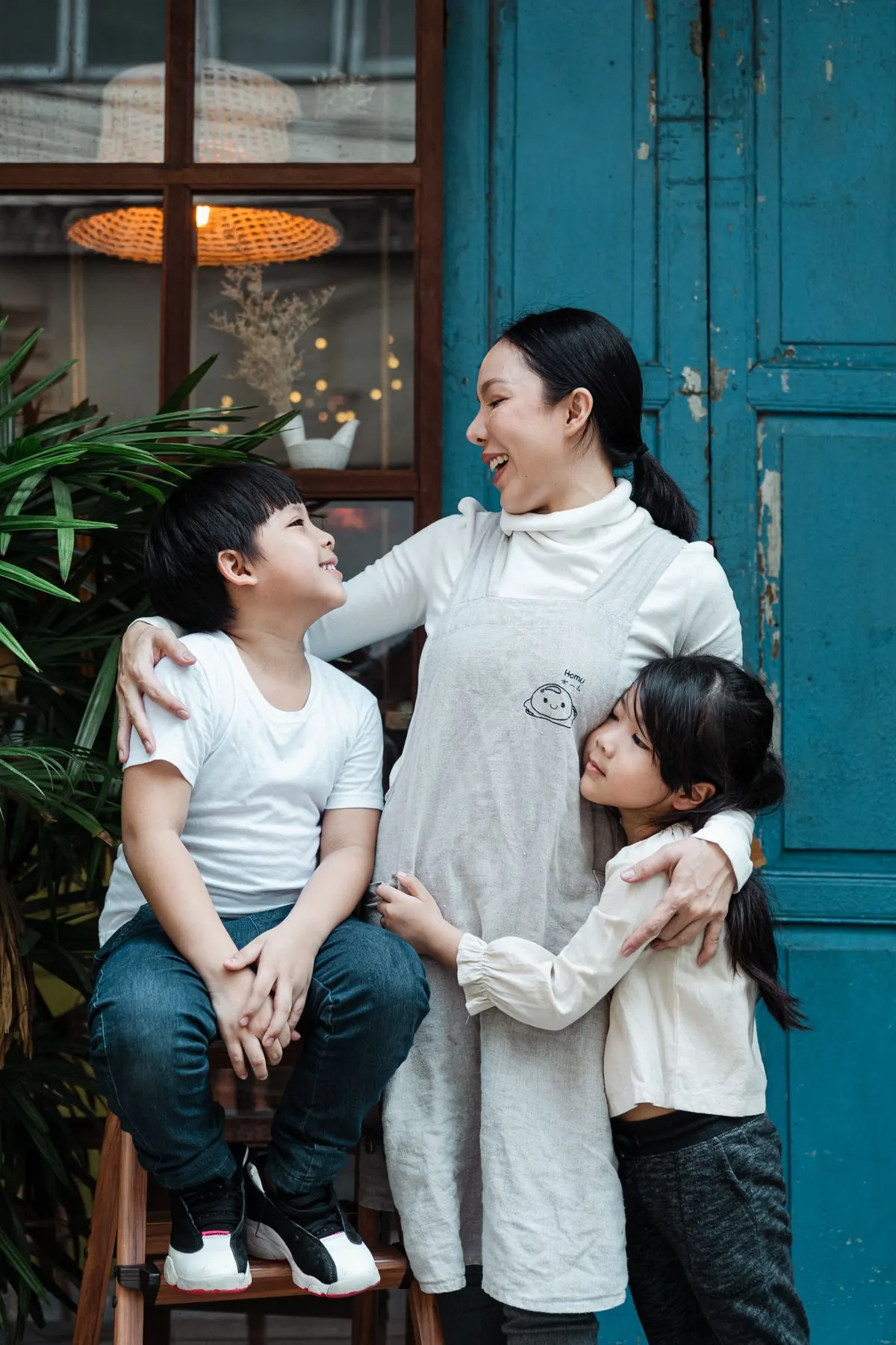Người mẹ cùng các con đứng trước cánh cửa màu xanh